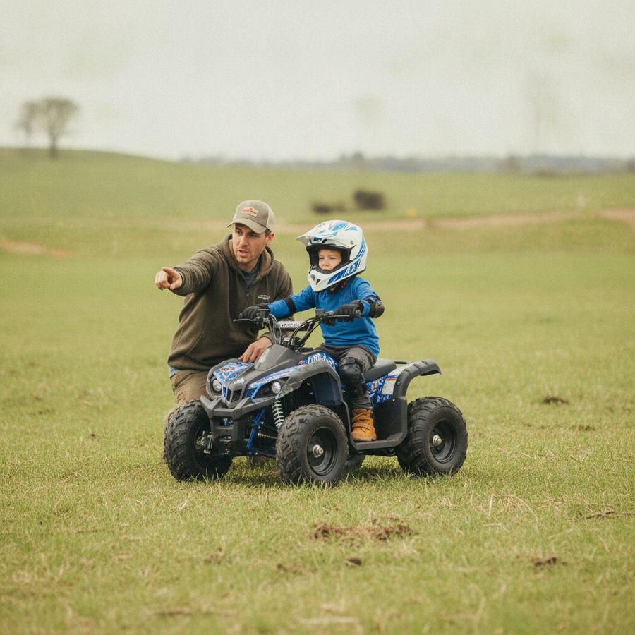 Kind met helm en beschermers op een quad terwijl een ouder dichtbij toezicht houdt op een open terrein.